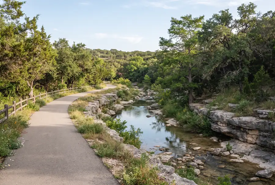 Paved greenway trail along a creek with limestone banks in Shavano Park, Texas